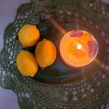 Large lemon candle burning with natural botanicals showing clean wax pool - handmade soy wax candle quality.