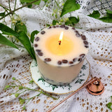 Coffee candle large pillar burning demonstration with coffee beans on antique teacup and fresh flowers