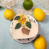 Heart-shaped candle with lemon decorations on a light blue surface with lemons around