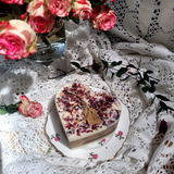 Beauty Scents large heart rose petals candle with dried botanicals on vintage floral plate surrounded by fresh pink roses and white lace