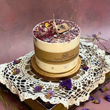 Handmade large pillar soy candle with rose petals decoration displayed on vintage crochet lace and wooden base