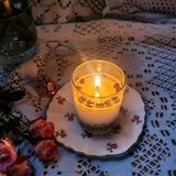 Small glass coffee bean candle burning with visible flame in glass container