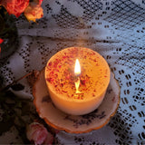 Burning small rose petals candle with warm flame on vintage plate surrounded by fresh pink roses and white lace