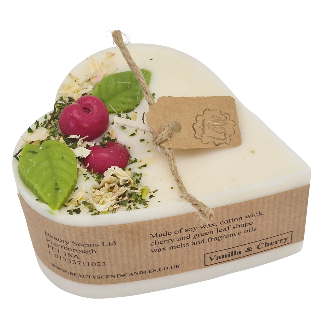 Heart-shaped candle with vanilla and cherry scented on the label, featuring Heart-shaped candle with wax cherries and green leafs on a white background.