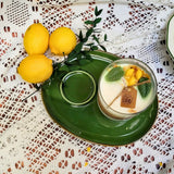 Candle with a 'love' tag on a green plate with lemons and leaves on a lace tablecloth