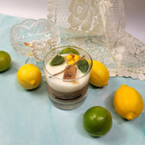 Small glass soy wax candle with lemon decoration with lemon and lime on a light blue surface
