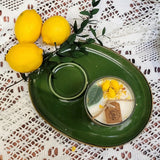 Green plate with a small cangle in glass with lemons, and greenery on a lace tablecloth.