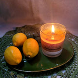 Candle with a label on a green plate with lemons, on a textured surface.