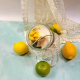 Candle in a glass jar with lemons on a light blue surface