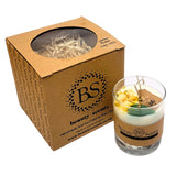 Glass candle with decorative elements next to a cardboard box labeled 'Beauty Scents'.