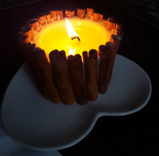 Beauty Scents soy candle burning with lantern effect showing melted wax pool and cinnamon stick decorations