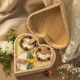 Heart-shaped wooden box with small round candles,  flowers on a rustic wooden surface close up