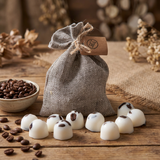 Beauty Scents Ten wax melts with coffee beans arranged around a grey linen bag, next to a small dish of coffee beans on a wooden table.