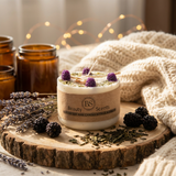 Candle with 'BS Scents' branding on a wooden surface with lavender and blackberries.