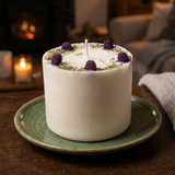 White candle with purple flowers on a green plate in a cozy setting