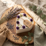 Heart-shaped candlewith lavender and eucalyptus on a wooden board with 'Beauty Scents Candles' branding.