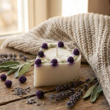 Beautyful candle with lavender flowers on a wooden surface with a knitted blanket in the background