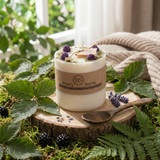 Decorative candle with natural elements on a wooden stump surrounded by greenery