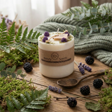 Candle with 'Beauty Scents' label surrounded by natural elements on a wooden surface