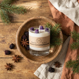 Candle in a wooden bowl with decorative elements on a wooden surface