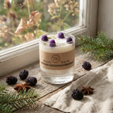 Candle with decorative elements on a wooden surface near a window