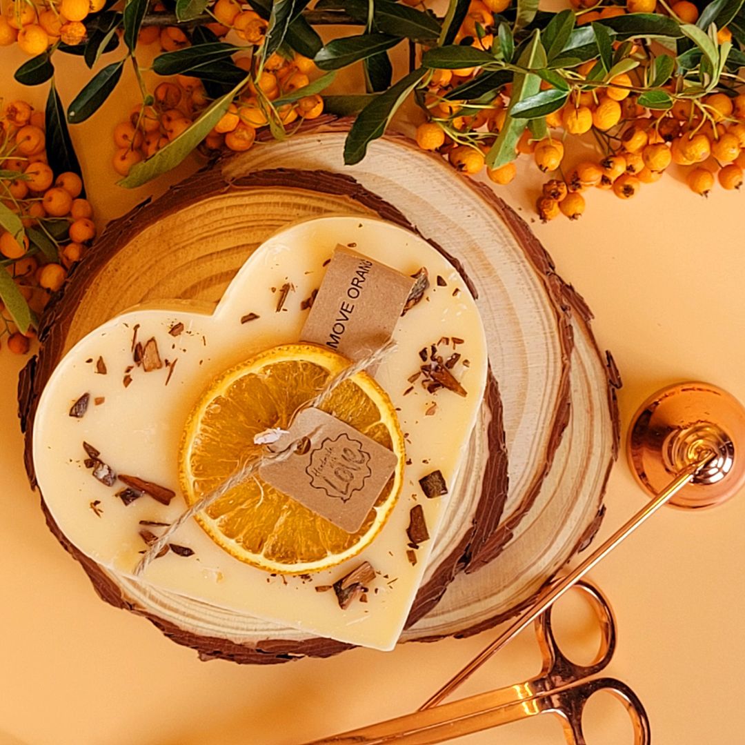 Handmade heart candle with orange slice and cinnamon decoration by Beauty Scents, romantic flat-lay with baby's breath flowers and sheer ribbon on natural wood