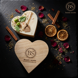 Heart-shaped wooden gift box with 'Beauty Scents' Heart Apple Candle, surrounded by dried fruits and herbs on a dark surface.