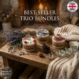 Three handmade soy candles—raspberry, wildflower, and rose petals—displayed on a rustic wooden table with lavender, pinecones, and a cozy knit blanket, set in front of a fireplace, “Made in UK” badge visible.