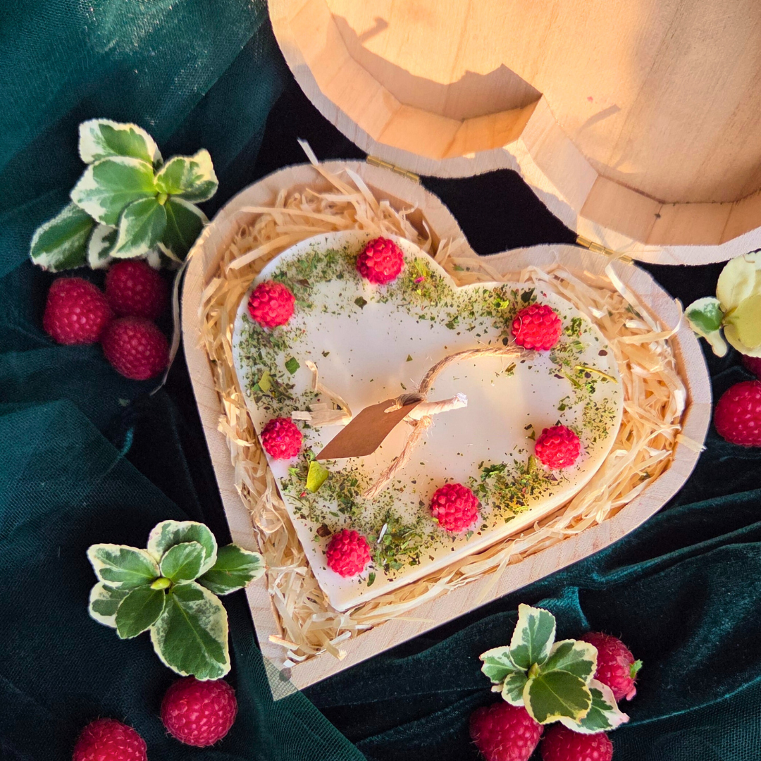 Top view of heart candle with raspberry details in a wooden gift box