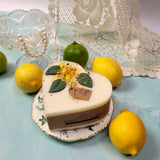 Heart-shaped candle with lemon and lime decorations on a decorative plate.