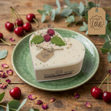 Beauty Scents Heart-shaped candle decorated with wax cherries and green leaf on a green plate with cherries and eucalyptus leaves on a wooden background.