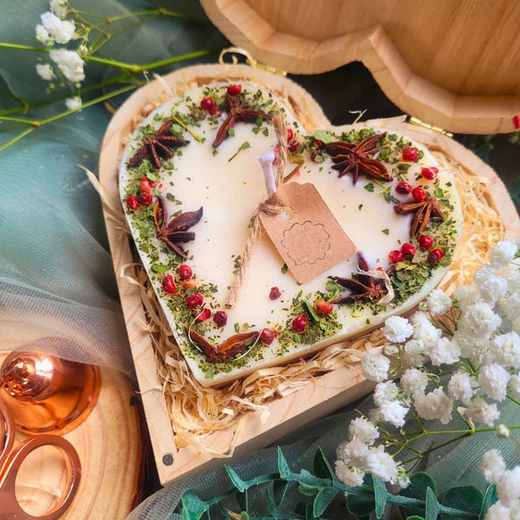 Large heart-shaped mulled wine scented candle with star anise and red berries in elegant wooden heart gift box with Christmas decorations