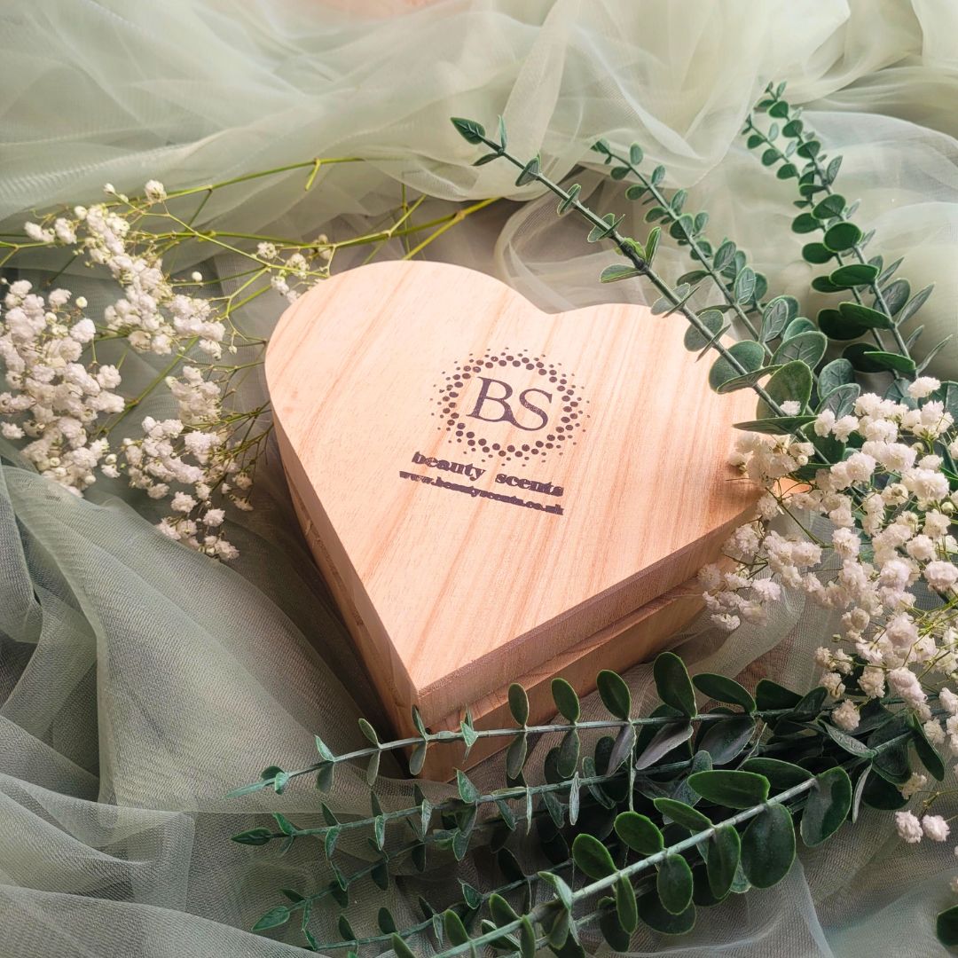 Heart Gift Box open view showing large heart-shaped orange cinnamon candle with natural botanical decorations and wood shavings