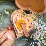 Large heart-shaped orange and cinnamon scented candle with detailed view of dried orange slices and cinnamon stick decorations