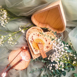 Large heart-shaped orange and cinnamon scented candle with dried orange slices and cinnamon sticks in romantic wooden heart gift box