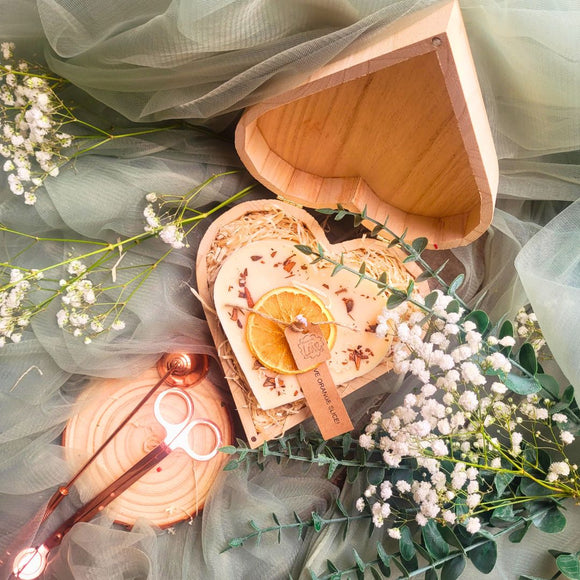 Large heart-shaped orange and cinnamon scented candle with dried orange slices and cinnamon sticks in romantic wooden heart gift box