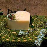 Candle with flowers on a green textured surface