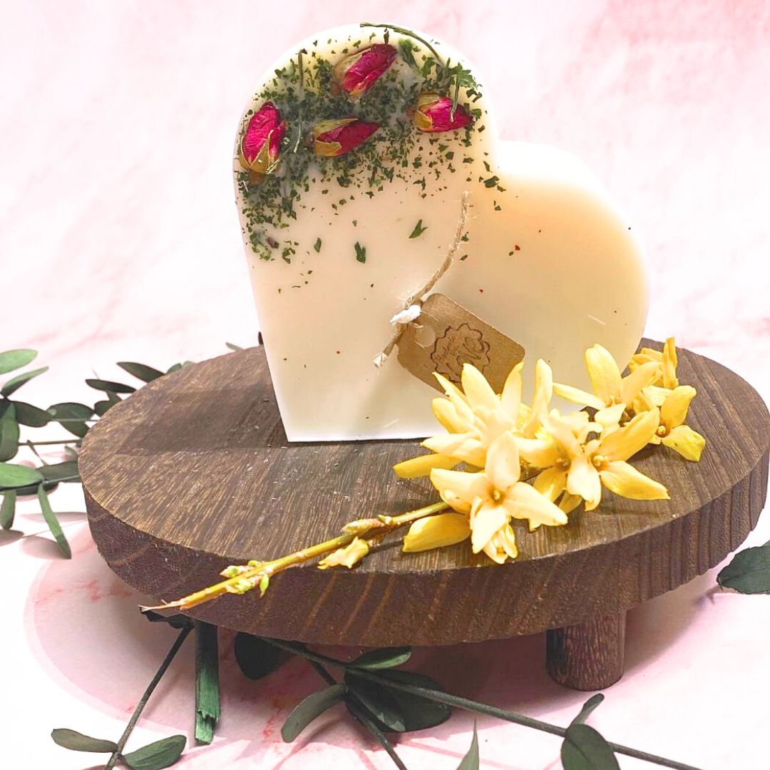 Decorative candle on a wooden stand with flowers and greenery