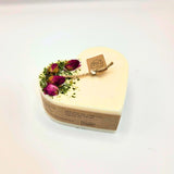 Heart-shaped candle with dried flowers and a tag on a white background