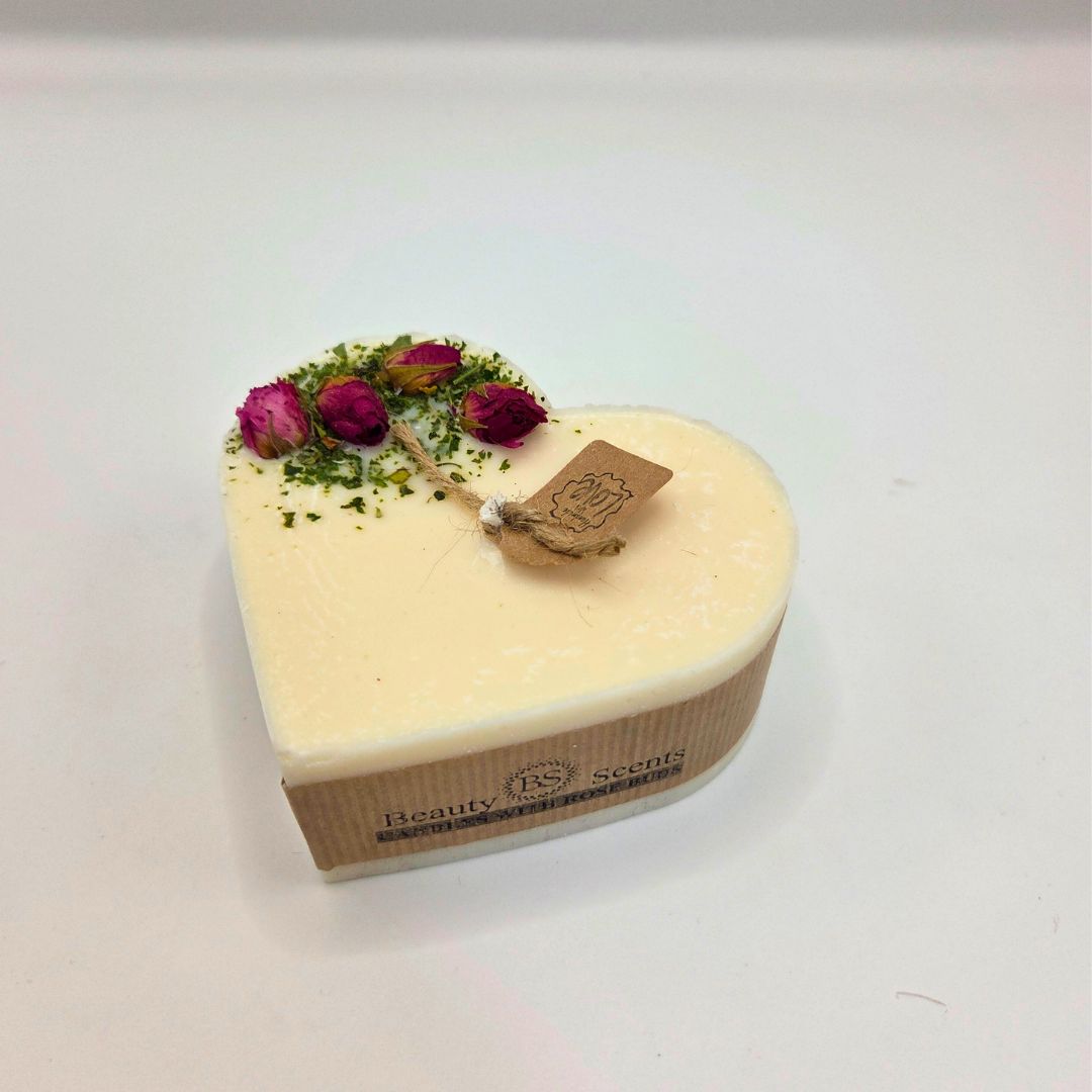 Heart-shaped candle with flowers and a tag on a white background
