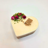 Heart-shaped candle with flowers and a tag on a white background