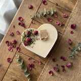 Heart-shaped candle with dried flowers and eucalyptus on a wooden surface