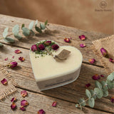 Heart-shaped candle with dried flowers on a wooden surface, featuring the brand 'BS Beauty Scents'.