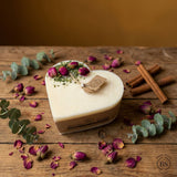 Heart-shaped candle with dried roses and eucalyptus on a wooden surface