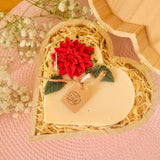 Large heart-shaped hollyberry scented candle with detailed view of winter poinsettia flower decoration in heart gift box