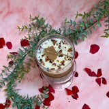 Large glass artisan candle with rose petals on beautiful crystal stand with romantic pink marble background
