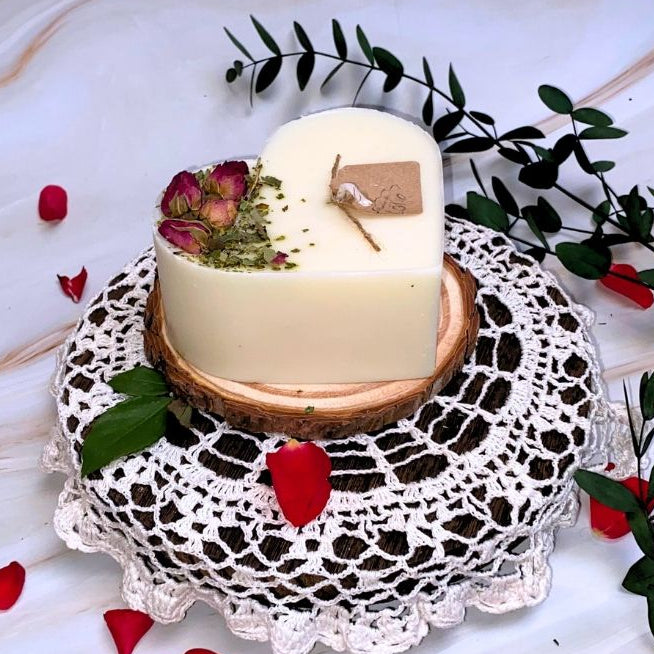 Heart-shaped candle on a decorative doily with flowers and leaves