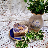 Large Heart Wild Flowers soy candle 500g with blue cornflowers decoration on blue ceramic plate, styled with white lace doilies, floral vase and fresh variegated foliage - romantic heart-shaped lifestyle photography