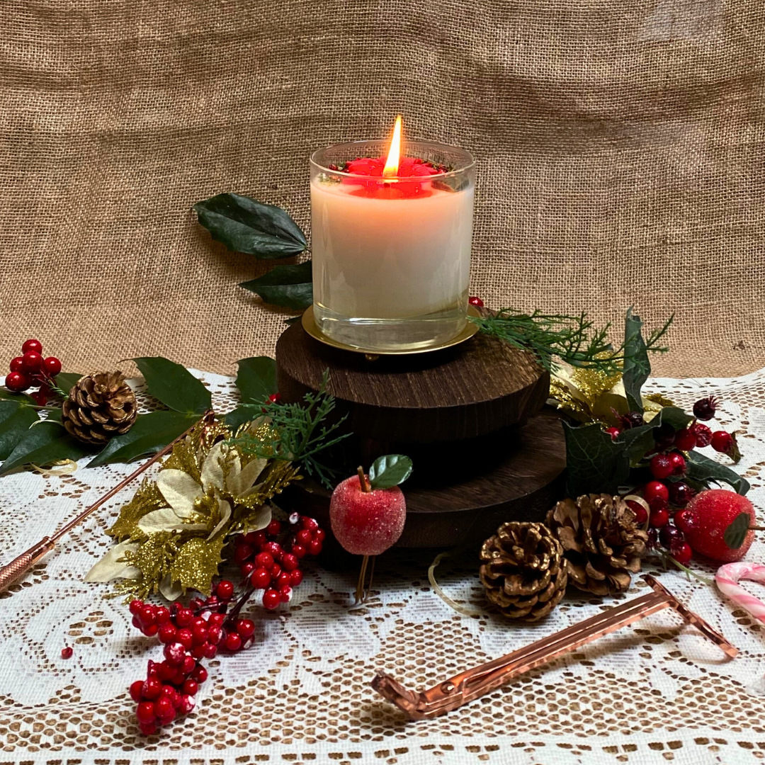 Large glass Winter Poinsettia candle top view with red poinsettia flower arrangement on white wax