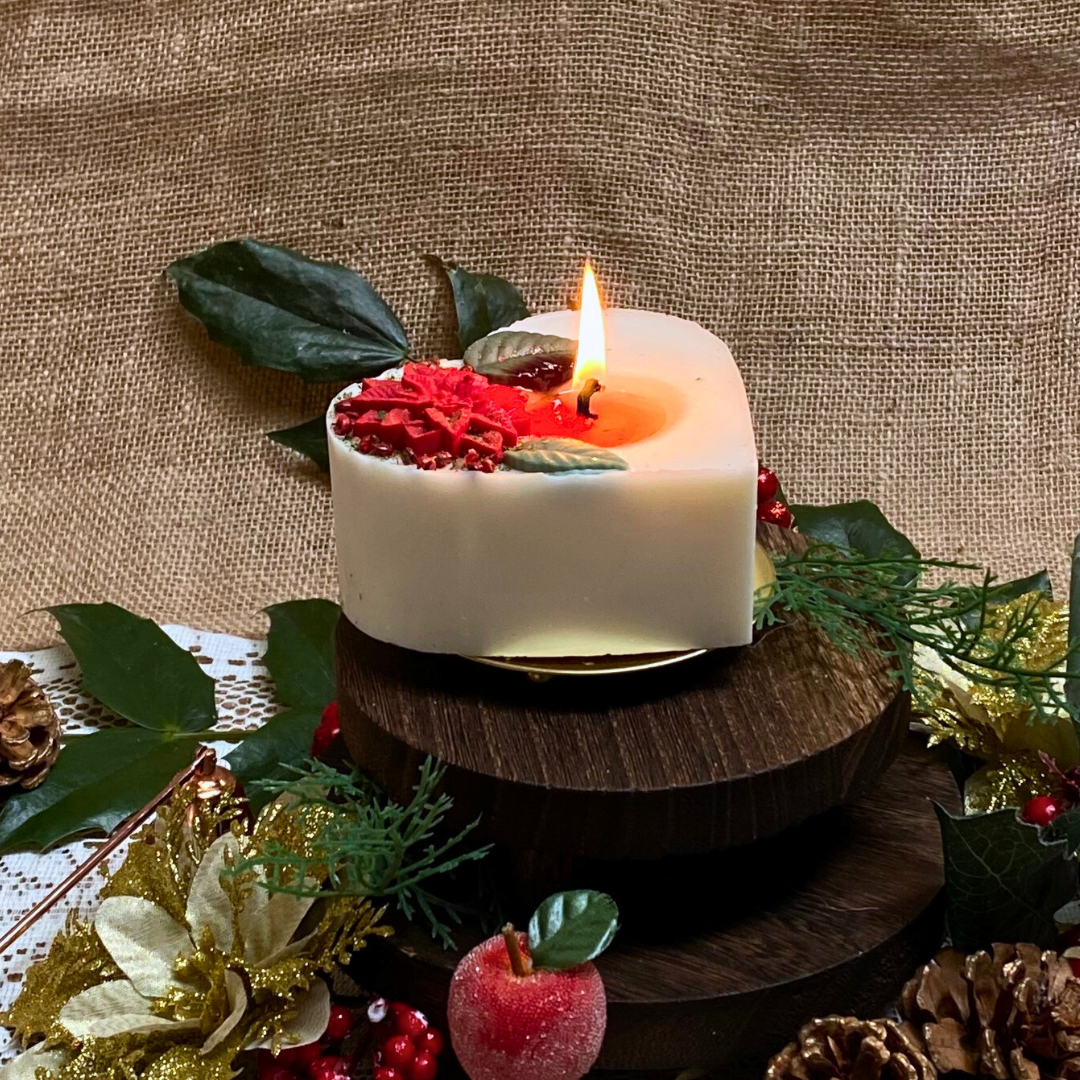 Large heart Winter Poinsettia candle top view with red poinsettia flower arrangement on white wax